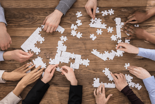 5-7 people working on putting together a table-top puzzle